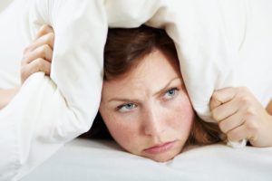 woman hiding under pillow